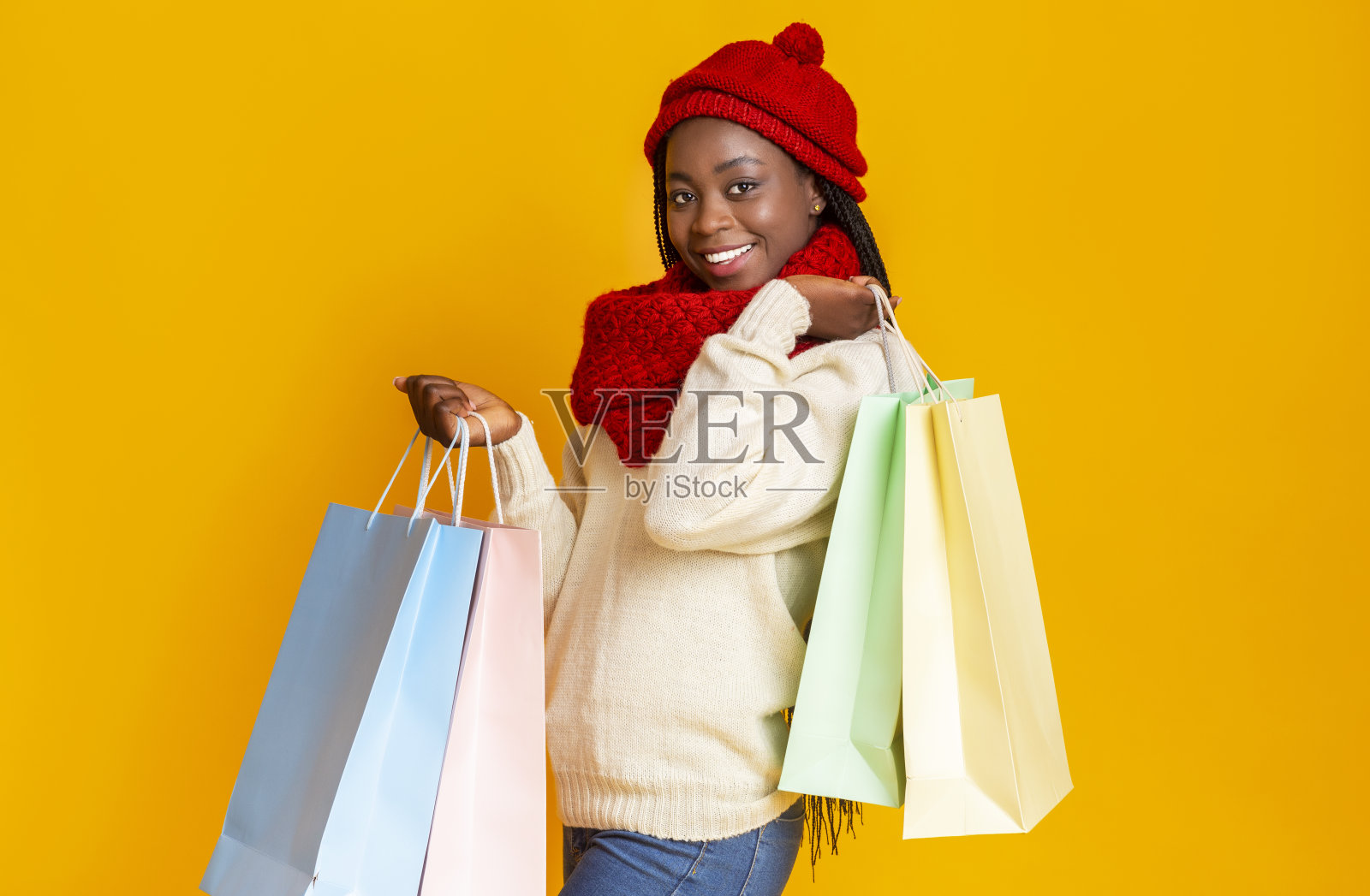 年轻开朗的黑人妇女用购物袋盖着黄色的背景照片摄影图片