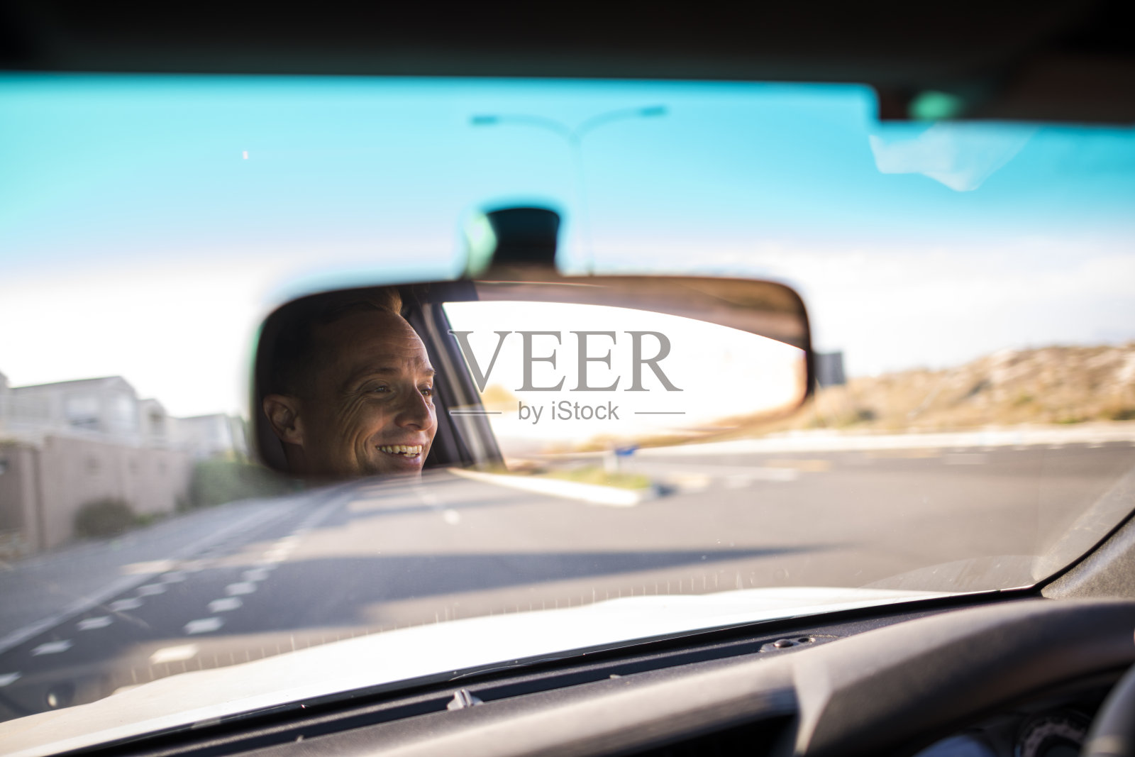 快乐男人的脸在后视镜开放的道路前面照片摄影图片