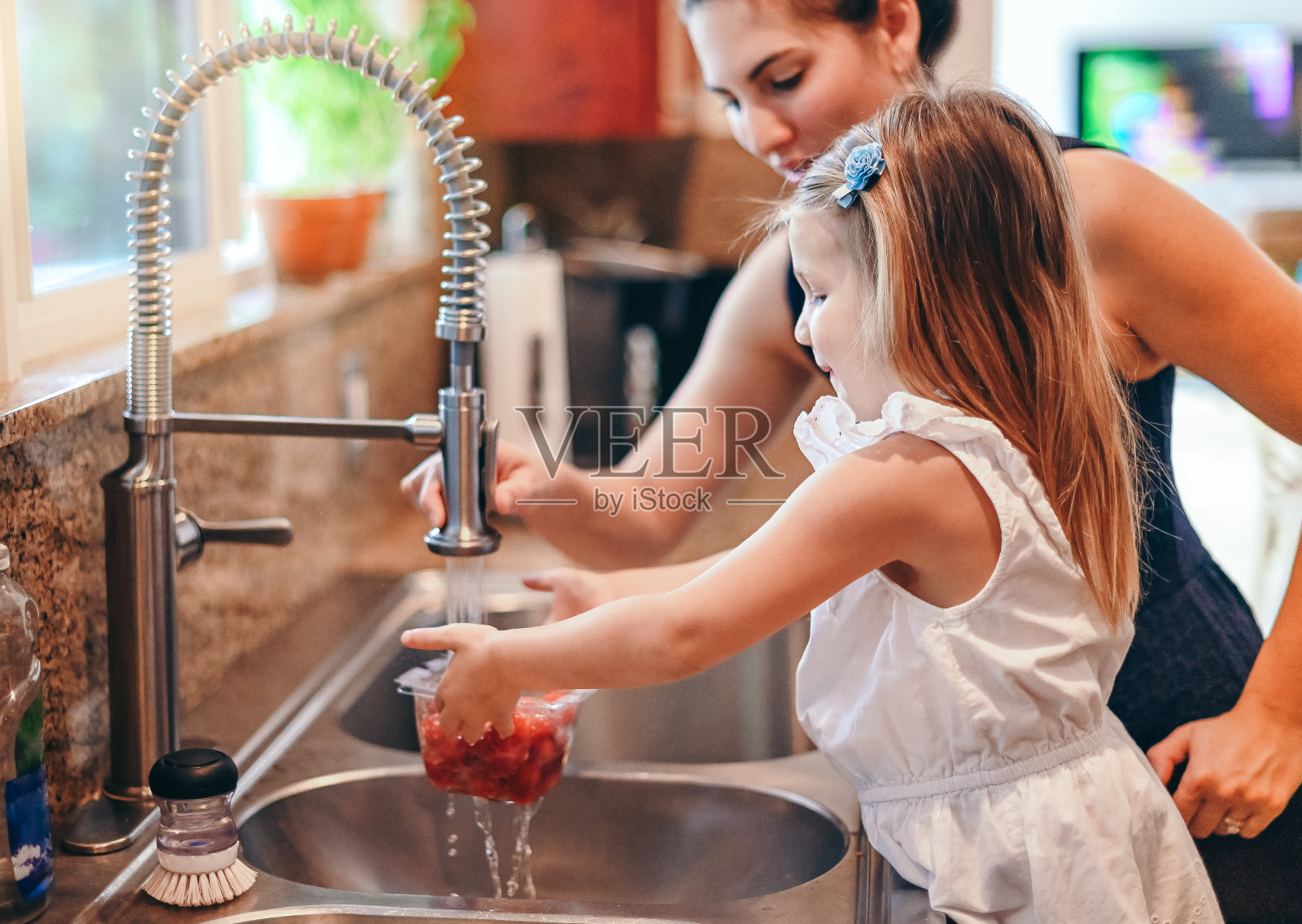 在厨房工作，母亲和女儿洗蔬菜照片摄影图片