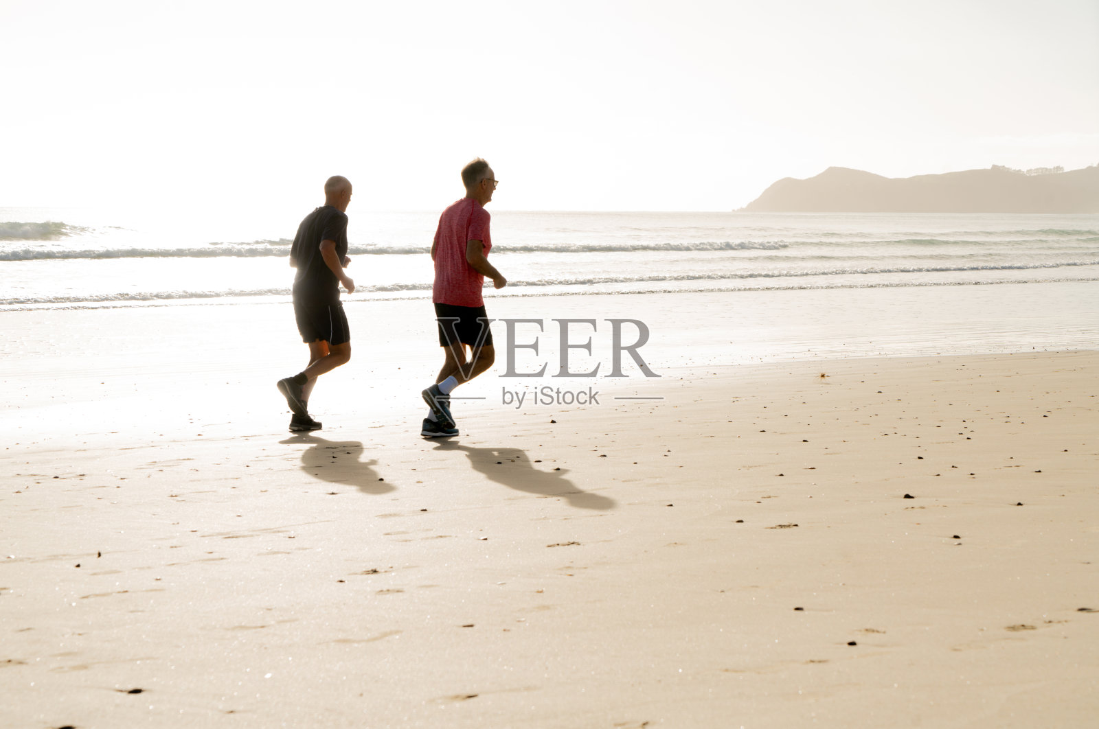 两位年长的男性朋友在海滩上度假，清晨跑步照片摄影图片