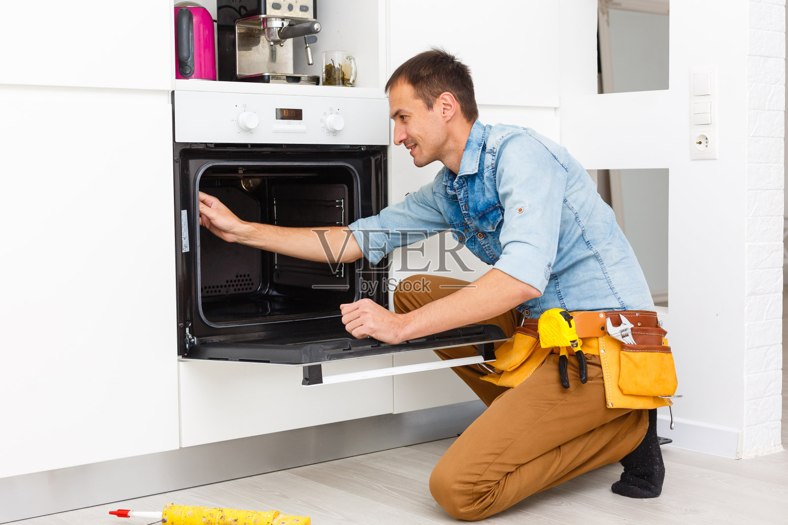 年轻修理工正在厨房安装电磁炉照片摄影图片