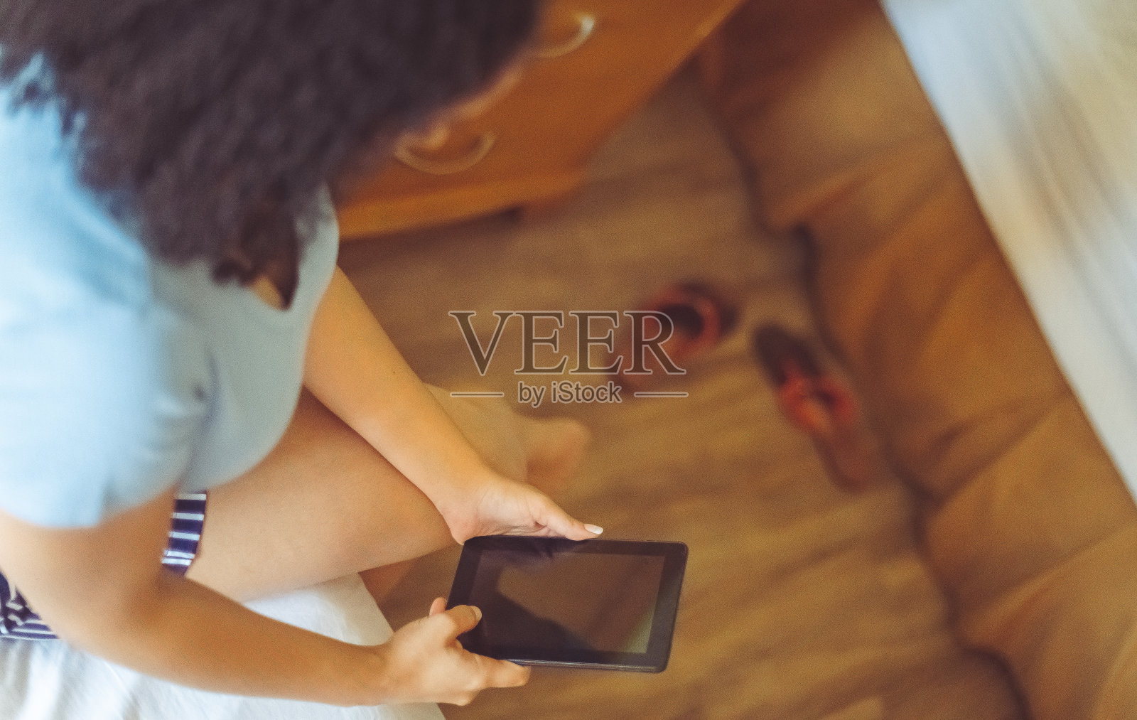 30多岁的混血女性在卧室里使用电子平板电脑照片摄影图片