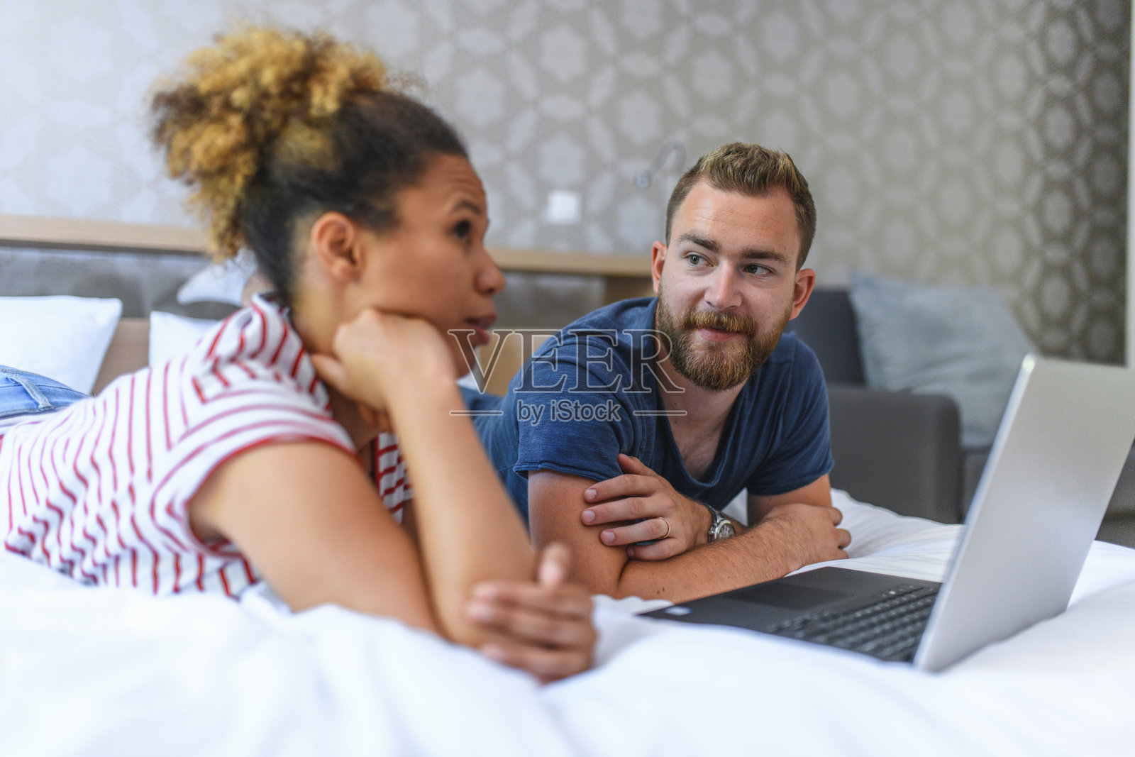 年轻的丈夫和妻子躺在床上讨论财务问题照片摄影图片