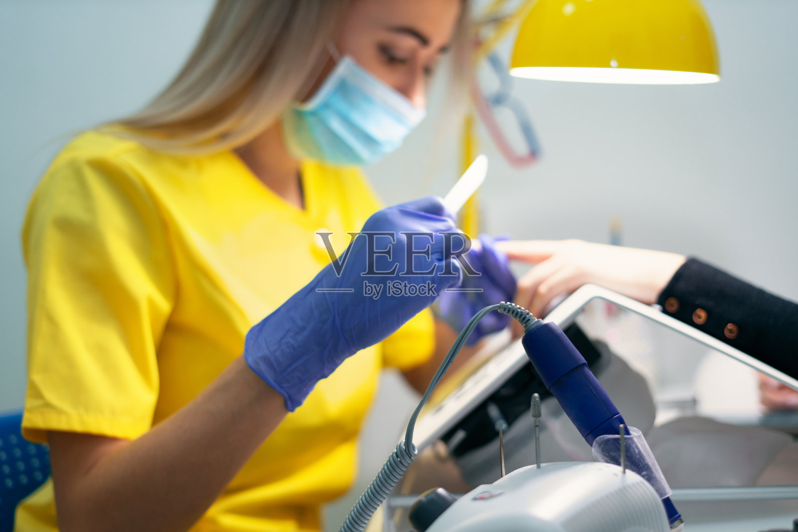 指甲护理。去沙龙修指甲。师傅给女孩修指甲，美丽又健康。修指甲的过程。掌握面具和手套。照片摄影图片