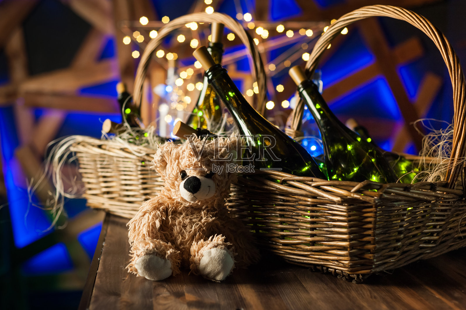 泰迪熊，香槟瓶与圣诞篮，金色花环在深棕色的木制背景，新年庆祝的概念照片摄影图片