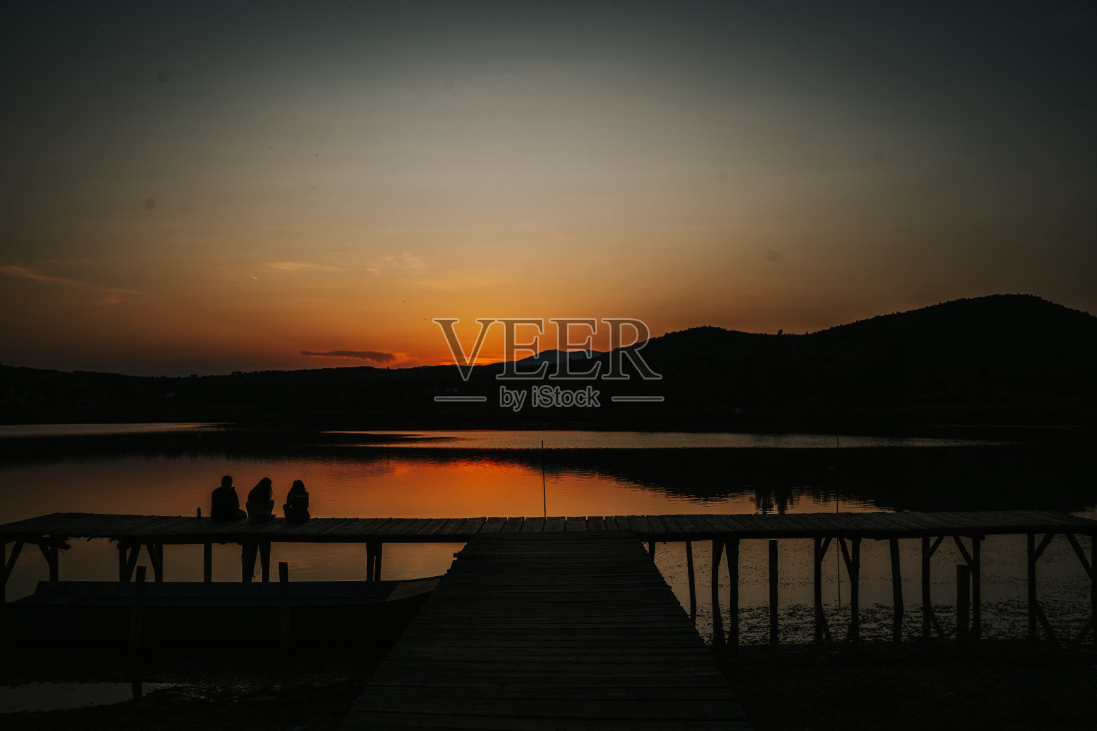 朋友们在湖边的码头上欣赏日落照片摄影图片