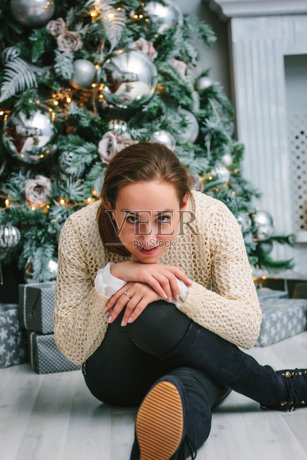 一个年轻女孩坐在圣诞树旁的肖像。照片摄影图片