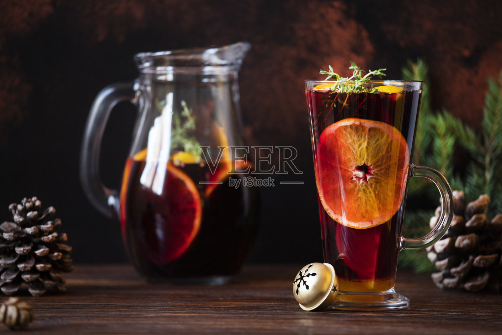 热葡萄酒——用红酒、柑橘和香料制成的热饮，摆放在圣诞装饰的木桌上。酒杯和酒瓶里放着热红酒。黑暗的背景。特写镜头,色彩斑斓,copyspace照片摄影图片