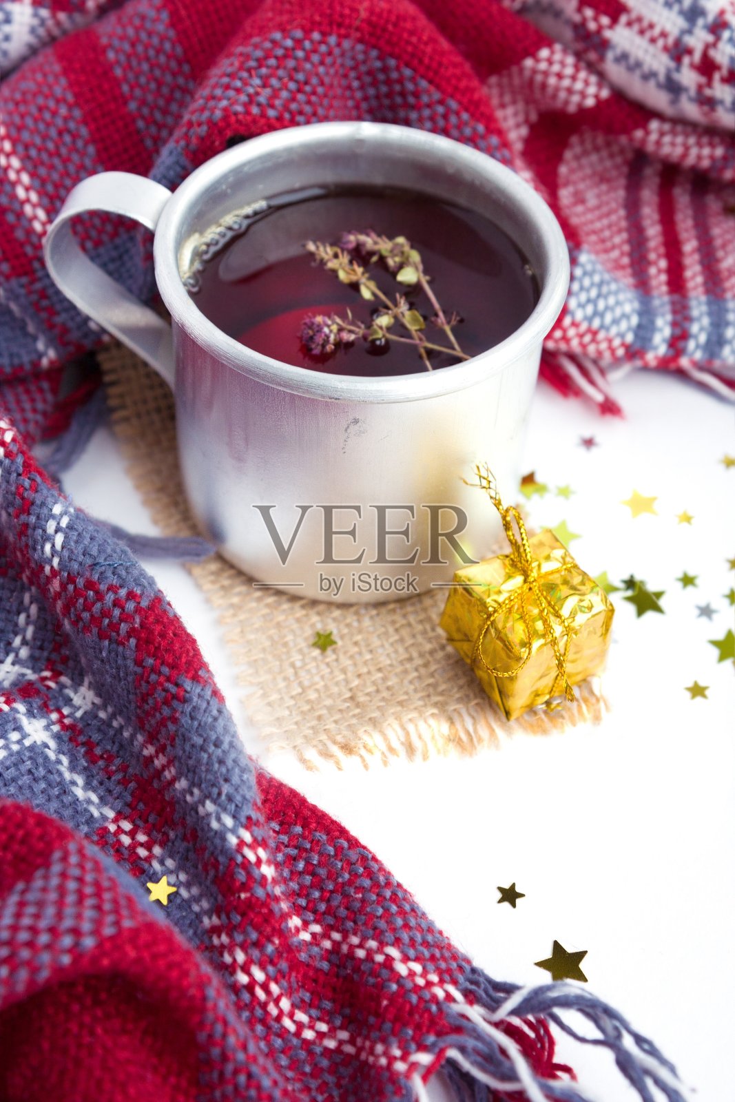 热的圣诞饮料红茶与百里香在马克杯与新年装饰。金色的礼物，格子图案和五彩纸屑在白色的背景。冬季俯视图。照片摄影图片
