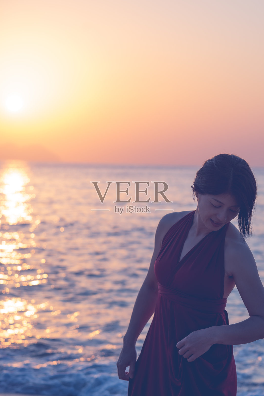 日落海滩上穿红衣服的女人照片摄影图片