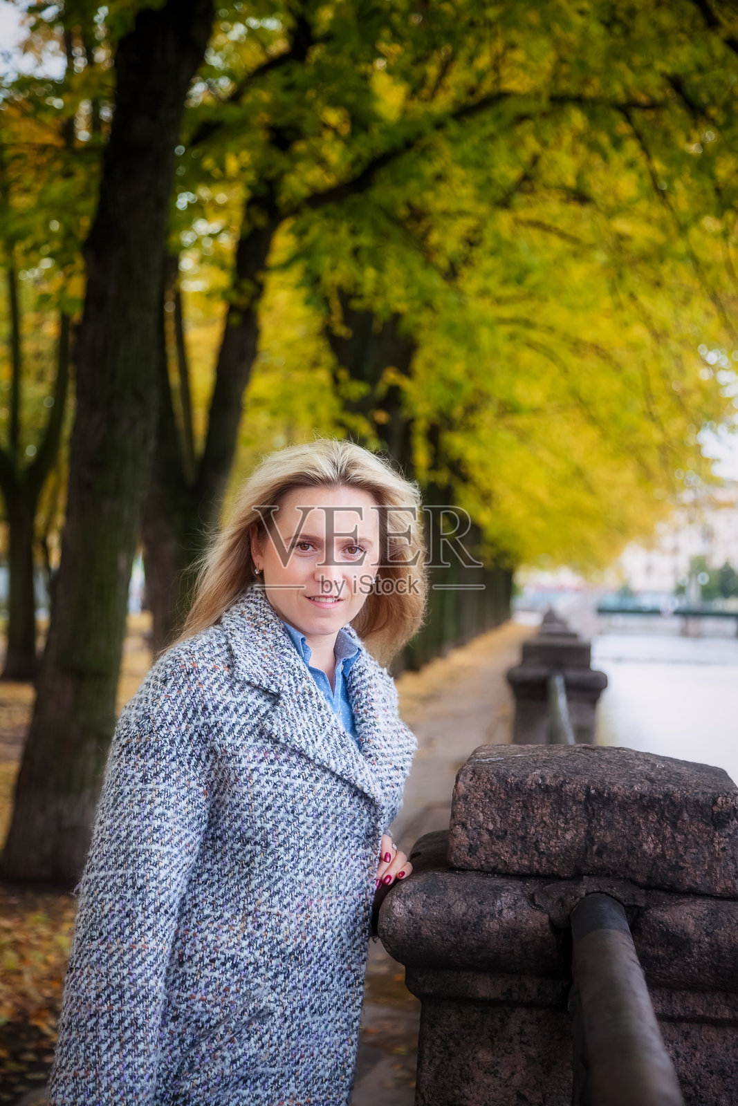 一名年轻女子在一个阳光明媚的秋天沿着圣彼得堡运河散步的肖像照片摄影图片