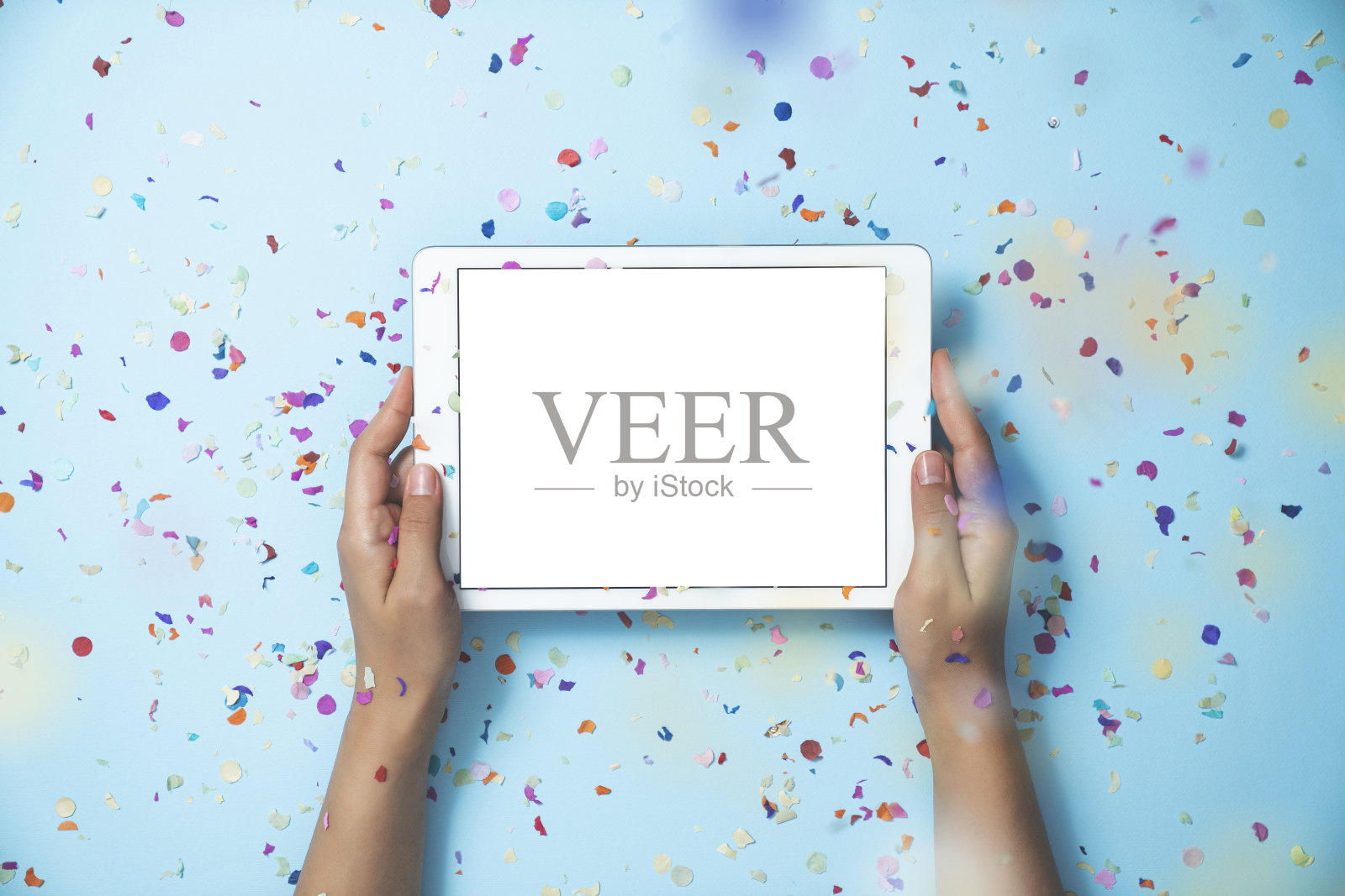 手持蓝色背景上的数字平板电脑照片摄影图片