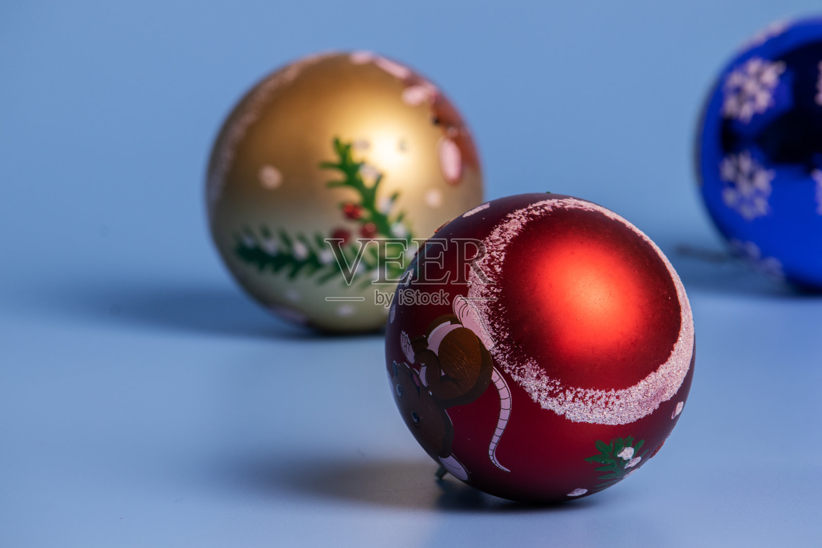 蓝色背景上的三个圣诞球。照片摄影图片