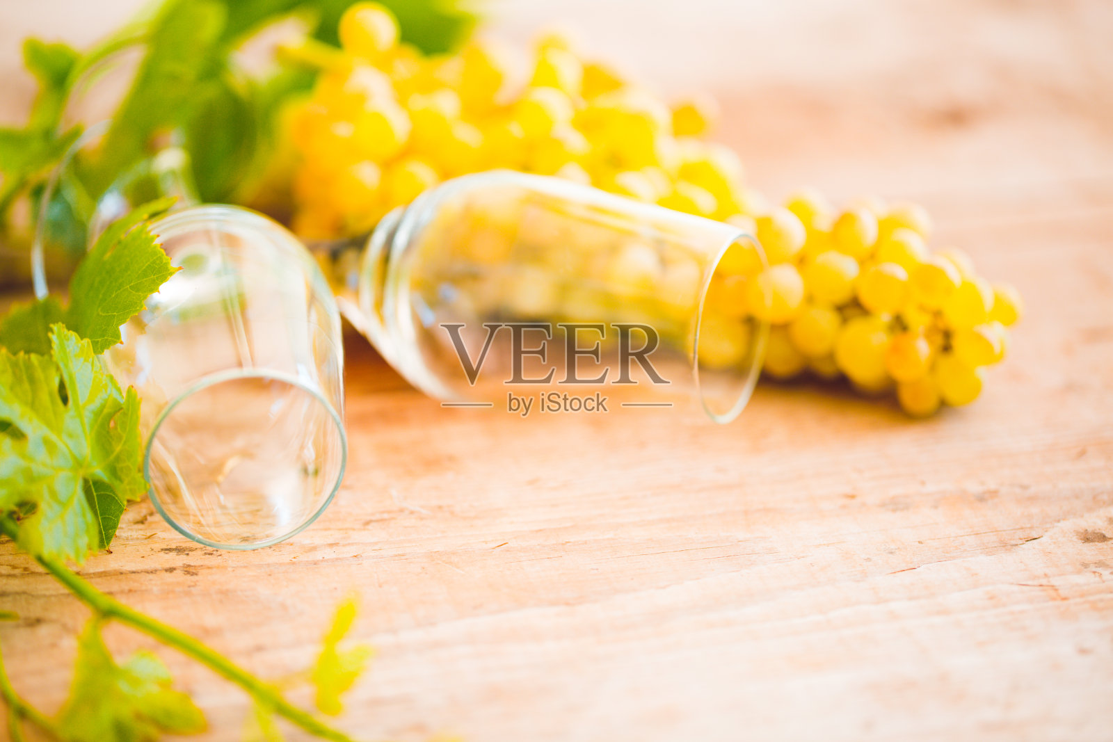 葡萄酒杯放在木制的乡村背景上，新鲜的黄红葡萄和绿叶放在破旧的桌子上，仿空间平铺，俯视图，意大利法国健康的酒庄美食，品酒照片摄影图片