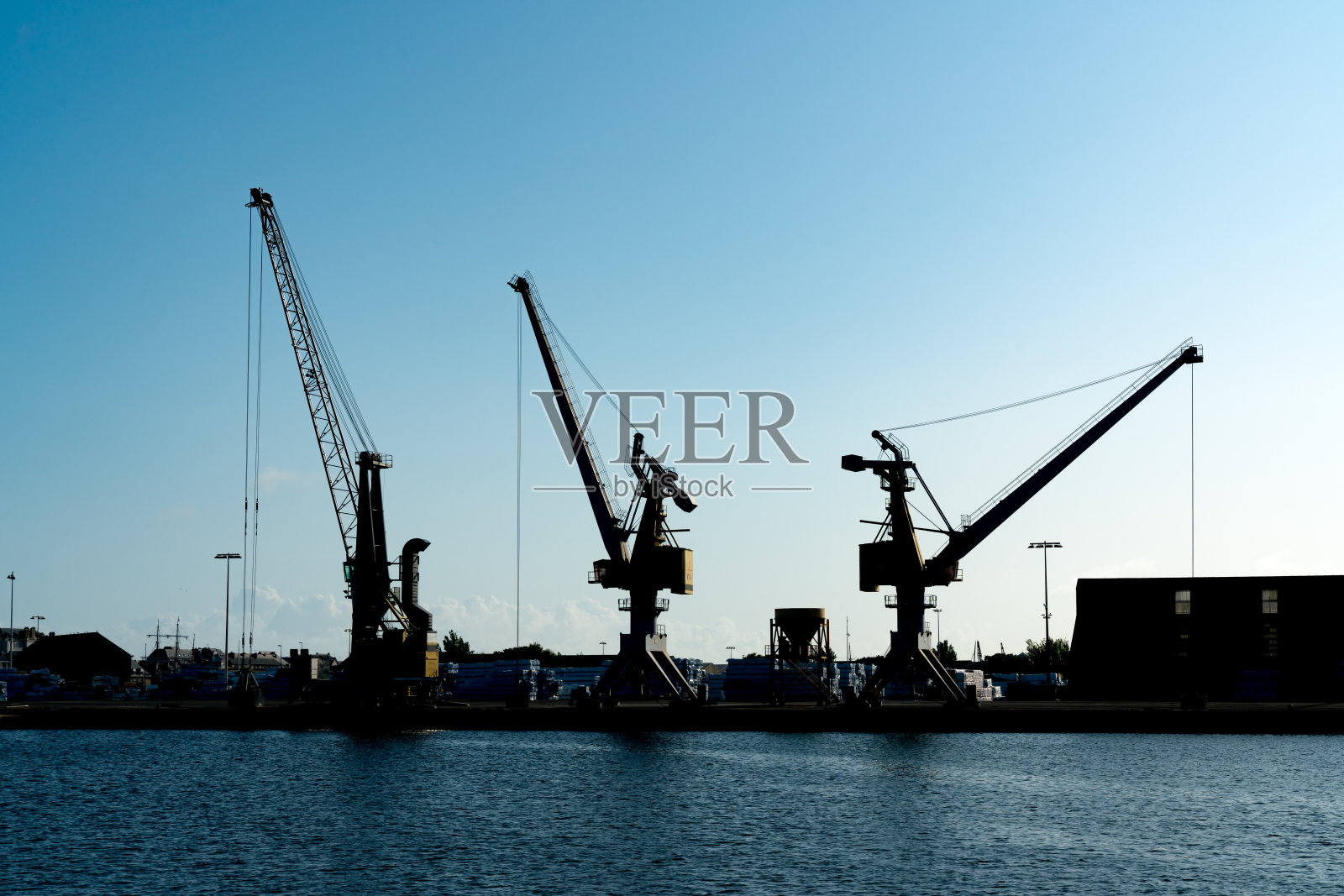 黄昏时分，湛蓝的夜空下，一个大型商埠的港口起重机的剪影照片摄影图片