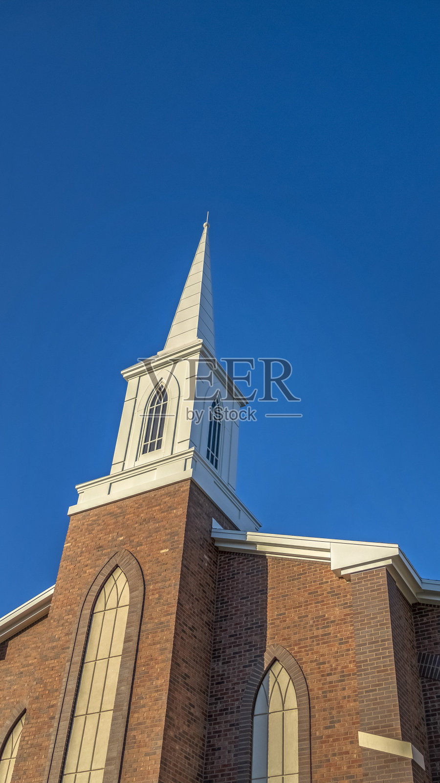 经典的红砖外墙和白色尖塔映衬着蓝色的天空照片摄影图片