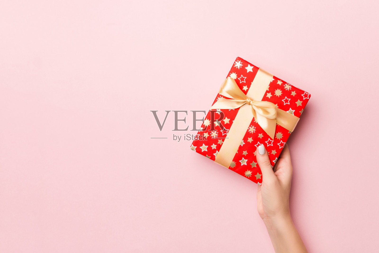 女人的手拿着带彩带的彩条礼盒，以活珊瑚为背景。圣诞概念或其他节日手工礼品盒，概念顶视图与拷贝空间照片摄影图片