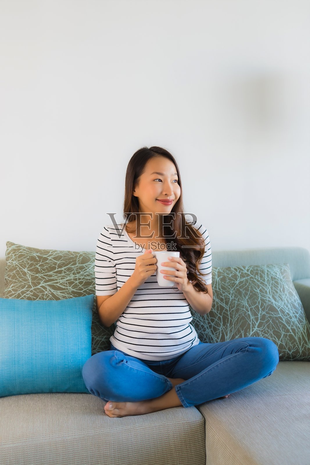肖像美丽的年轻亚洲女人在沙发上与咖啡杯照片摄影图片