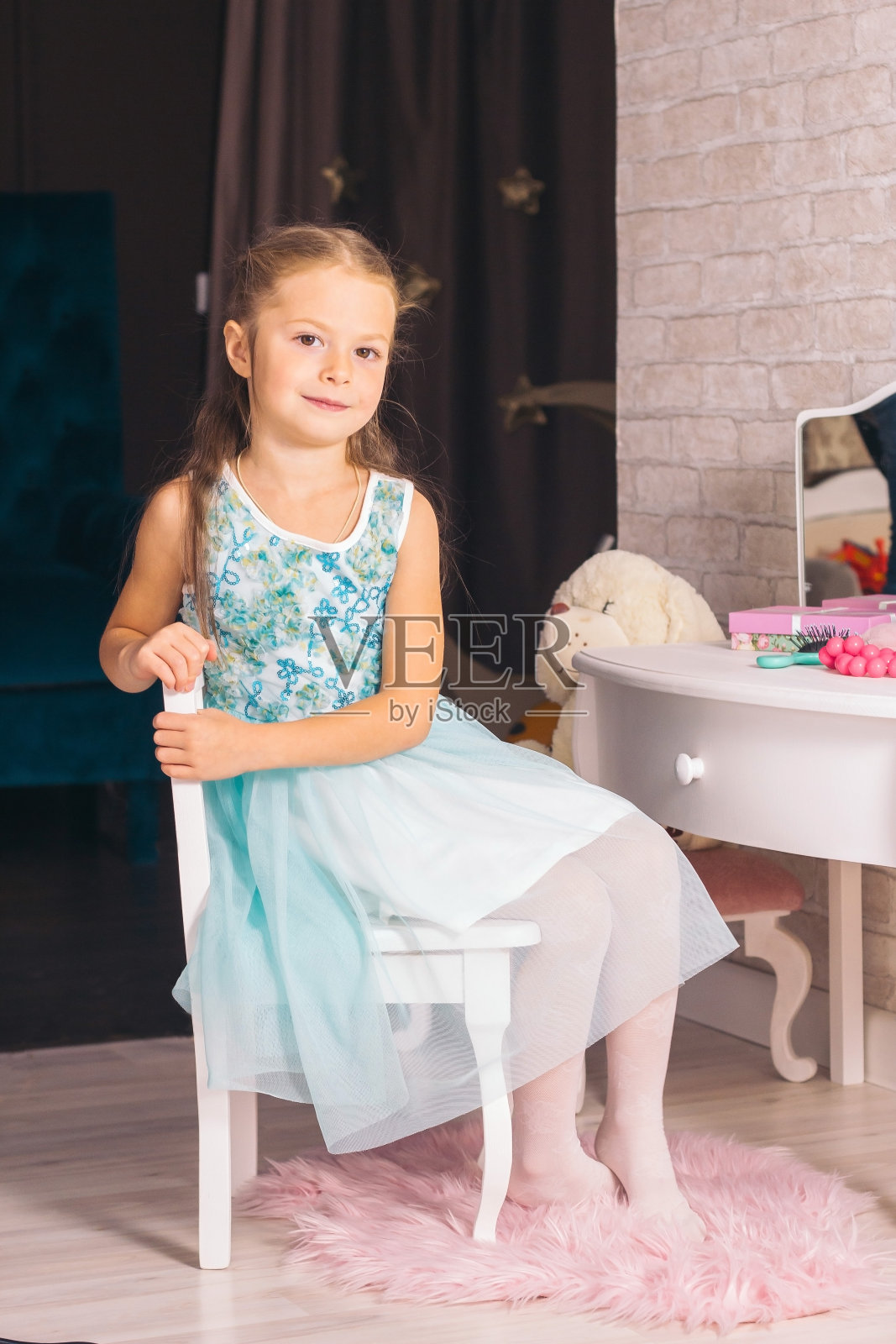 优雅的白人女孩坐在梳妆台上的椅子上，看着镜头照片摄影图片