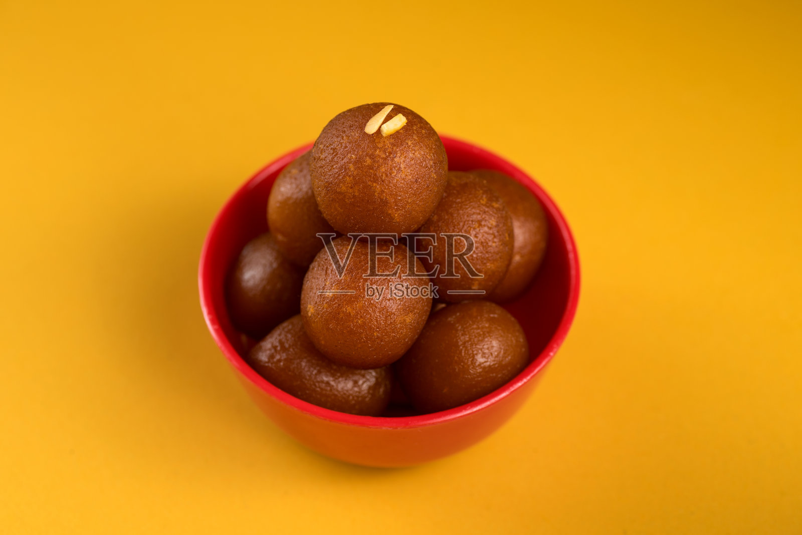 印度甜点或甜食:黄底的碗里的古拉佳蒙。照片摄影图片