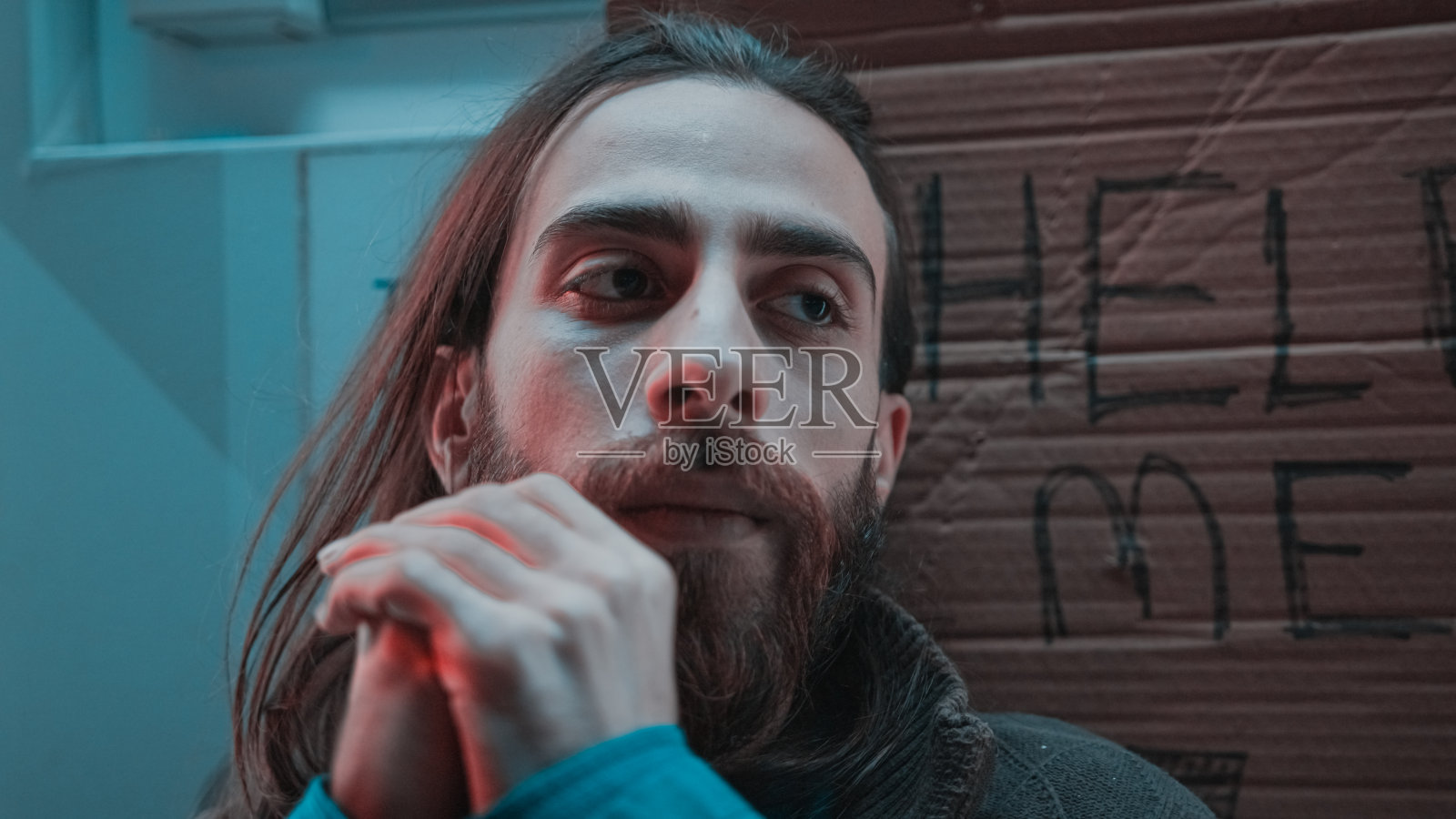 一个长头发、留着胡子的无家可归者正在寻求帮助。无家可归的概念。照片摄影图片