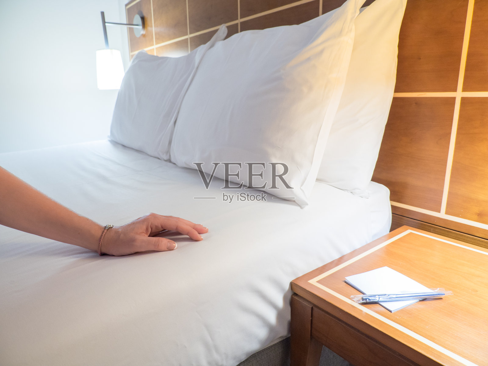 优雅舒适的家庭和酒店卧室室内。女手在床上，白色被褥。放松时间，假期，周末和旅游的概念。照片摄影图片