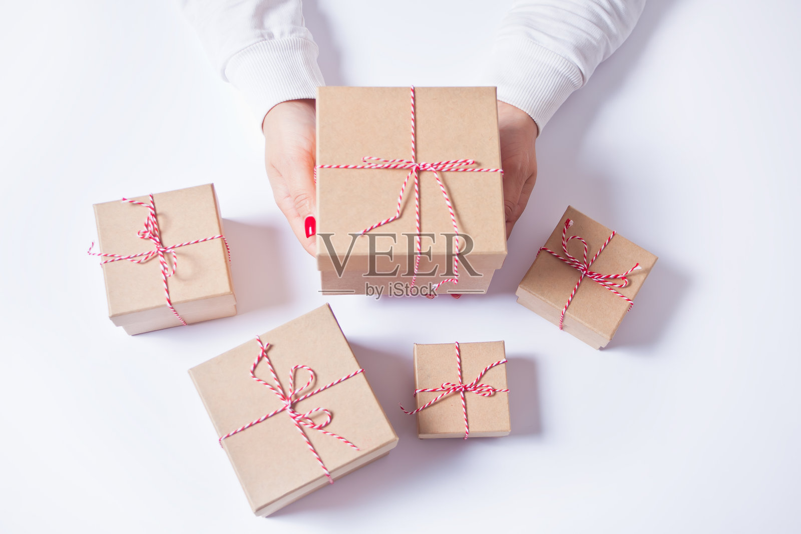 在白色的背景上，一个女人手里拿着一个圣诞礼物盒照片摄影图片