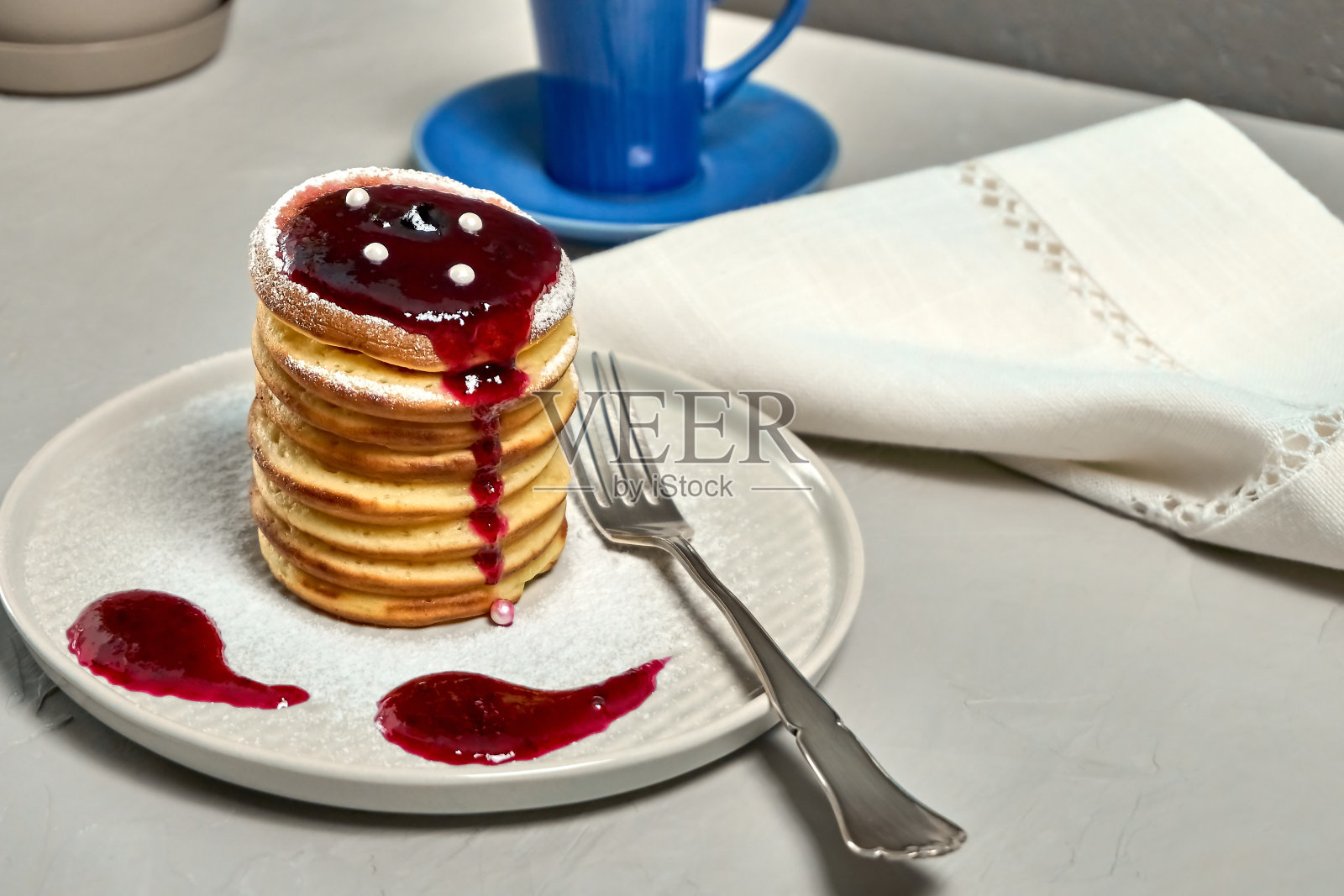 灰色的桌子上放着自制的煎饼和枫糖浆照片摄影图片