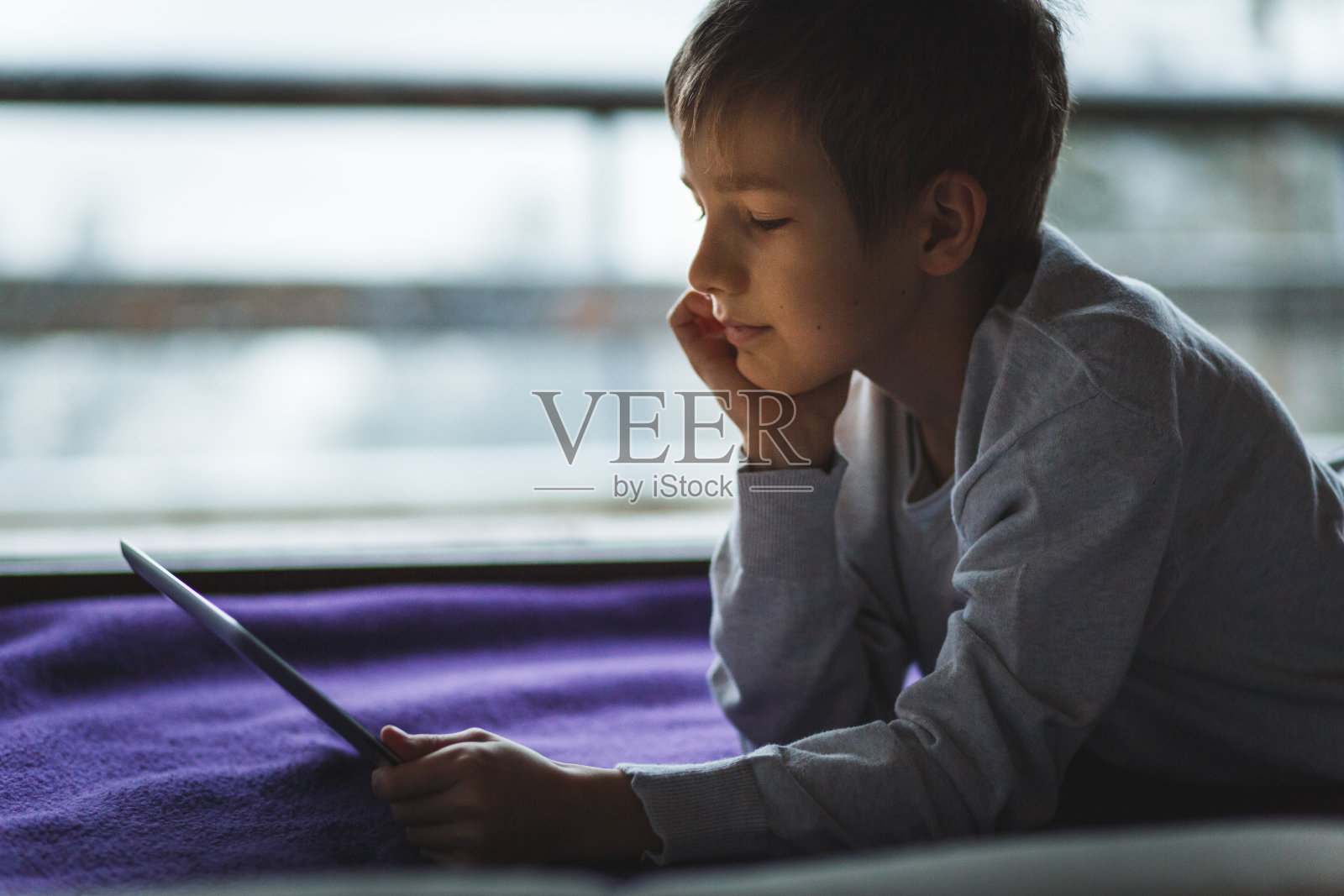 男孩在他的数码平板电脑上看卡通片照片摄影图片