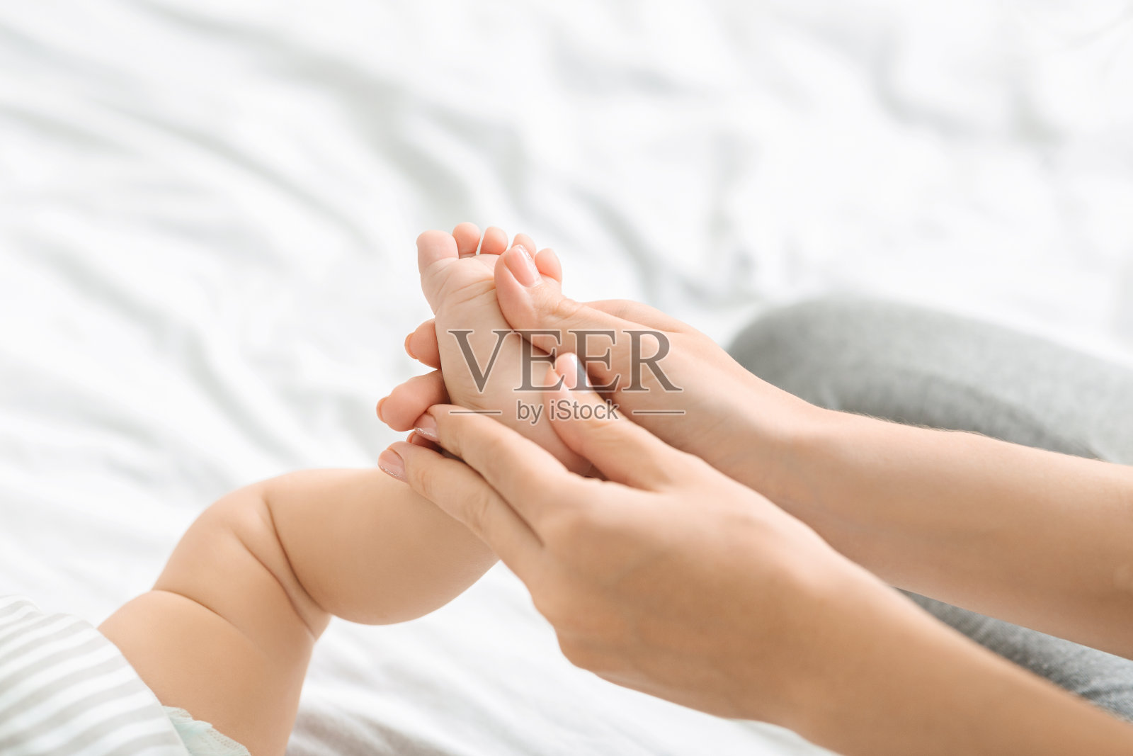 妈妈按摩小婴儿的脚部，做加强体操照片摄影图片
