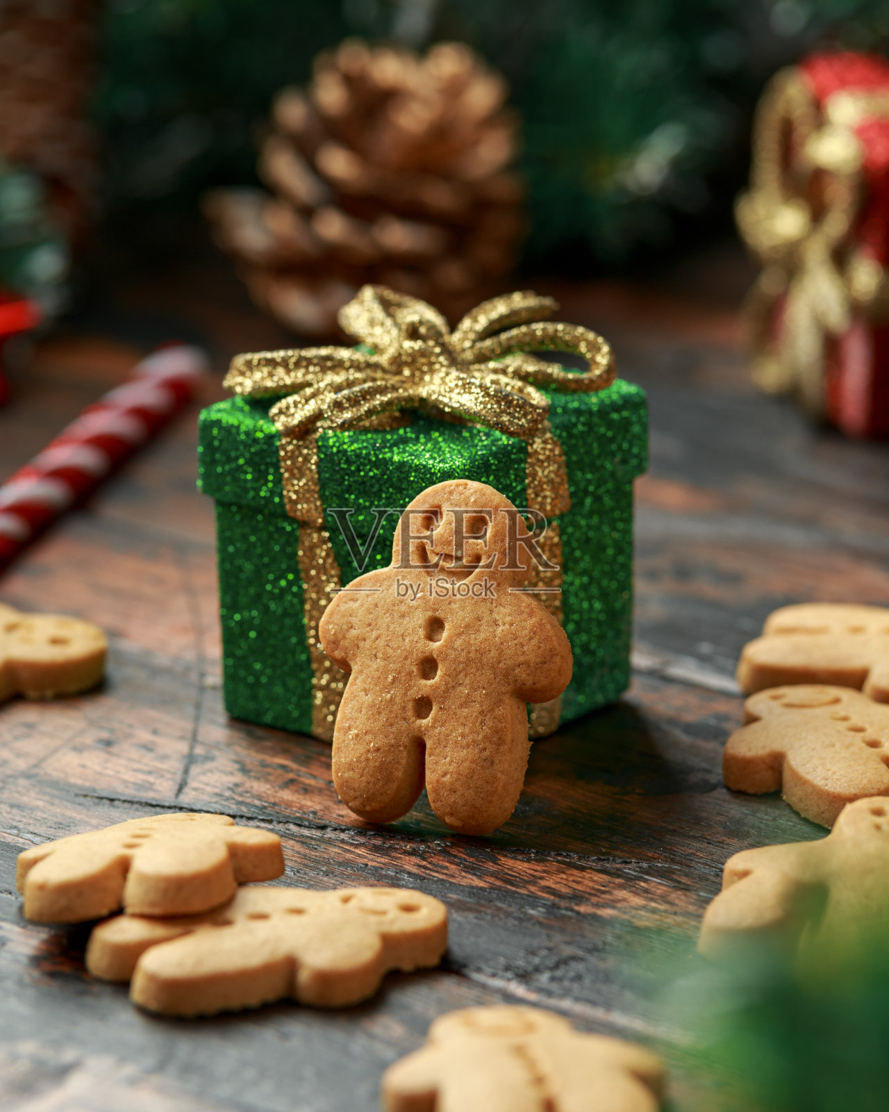 圣诞姜饼人用装饰、礼物、绿色树枝放在木桌上照片摄影图片