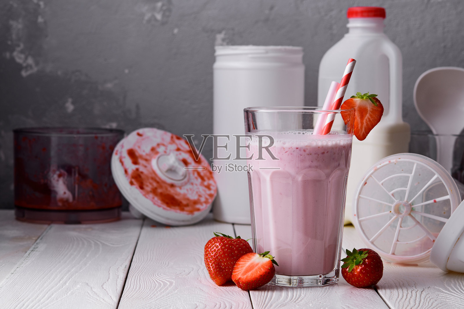 白色木质背景上的草莓蛋白奶昔。桌上放着新鲜的草莓奶昔。一杯草莓奶昔。照片摄影图片