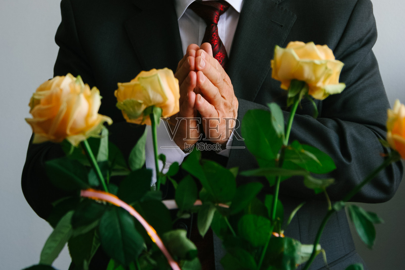 穿着西装，捧着玫瑰花的男人照片摄影图片