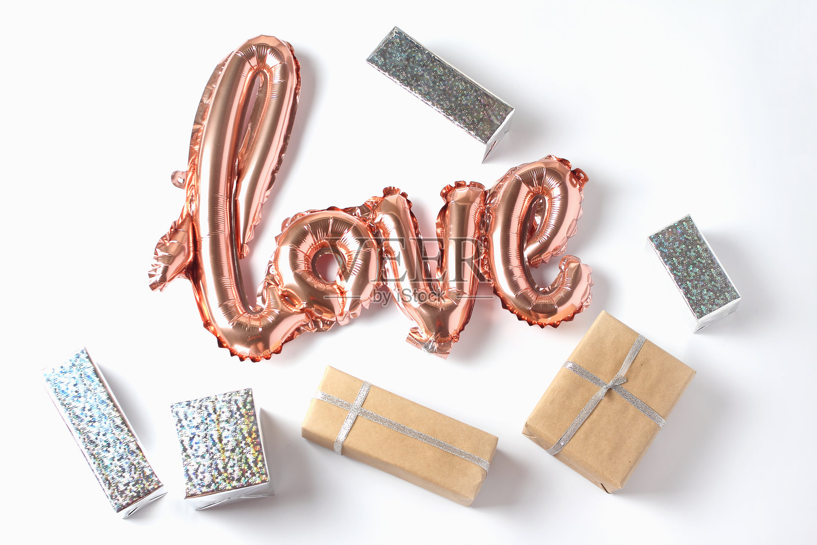 题词爱的形式在一个粉红色的金色气球在白色的背景。不同大小的礼品盒。平躺，俯视图照片摄影图片