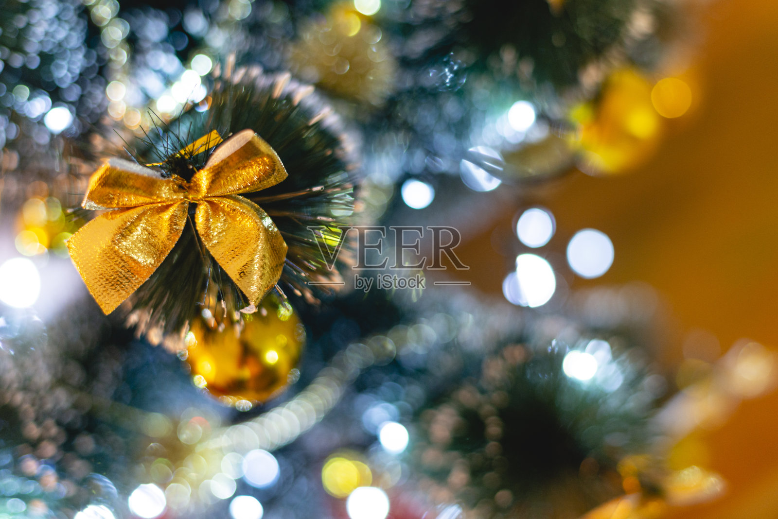 人造圣诞树的细节与灯和金色的装饰品。在前景中聚焦照片摄影图片