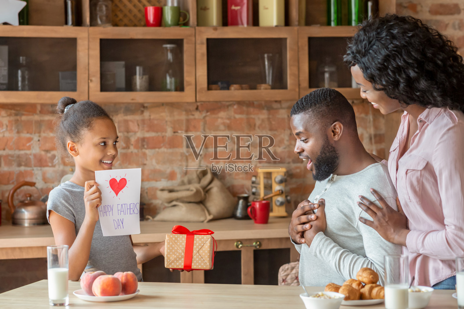 妻子和女儿在父亲节向惊奇的父亲问候照片摄影图片