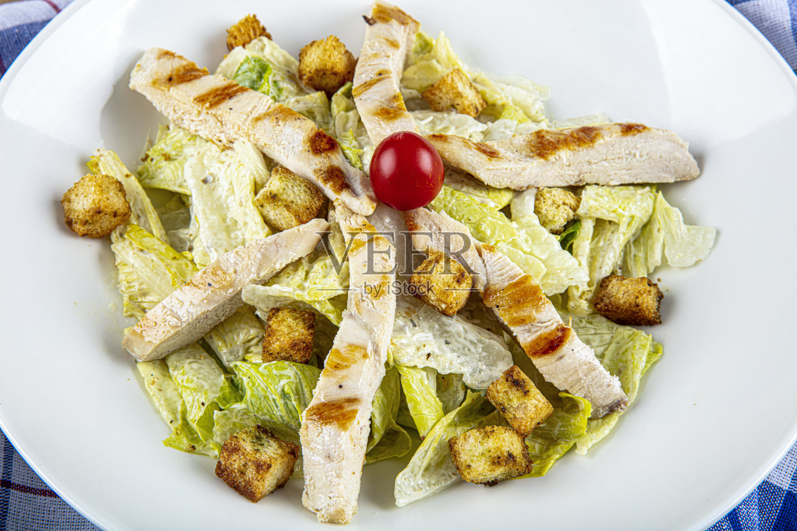 美味的凯撒沙拉配烤鸡丁。鸡肉凯撒沙拉，圣女果，生菜。照片摄影图片