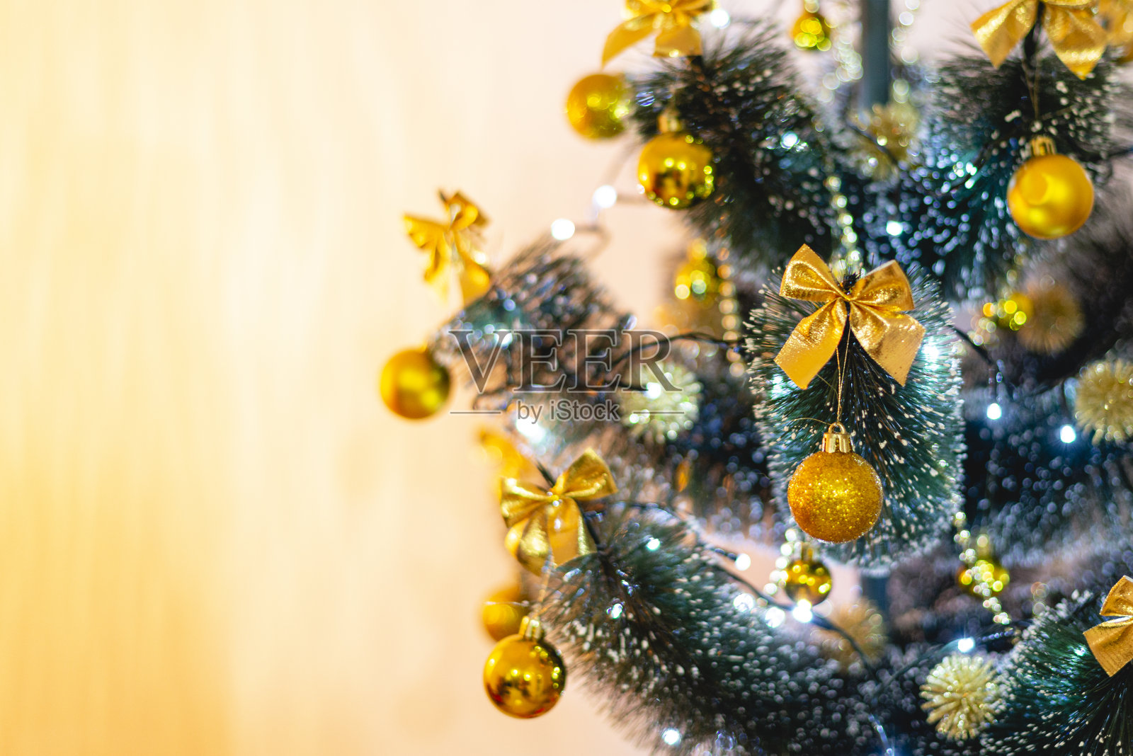 人造圣诞树的细节与灯和金色的装饰品。在前景中聚焦照片摄影图片