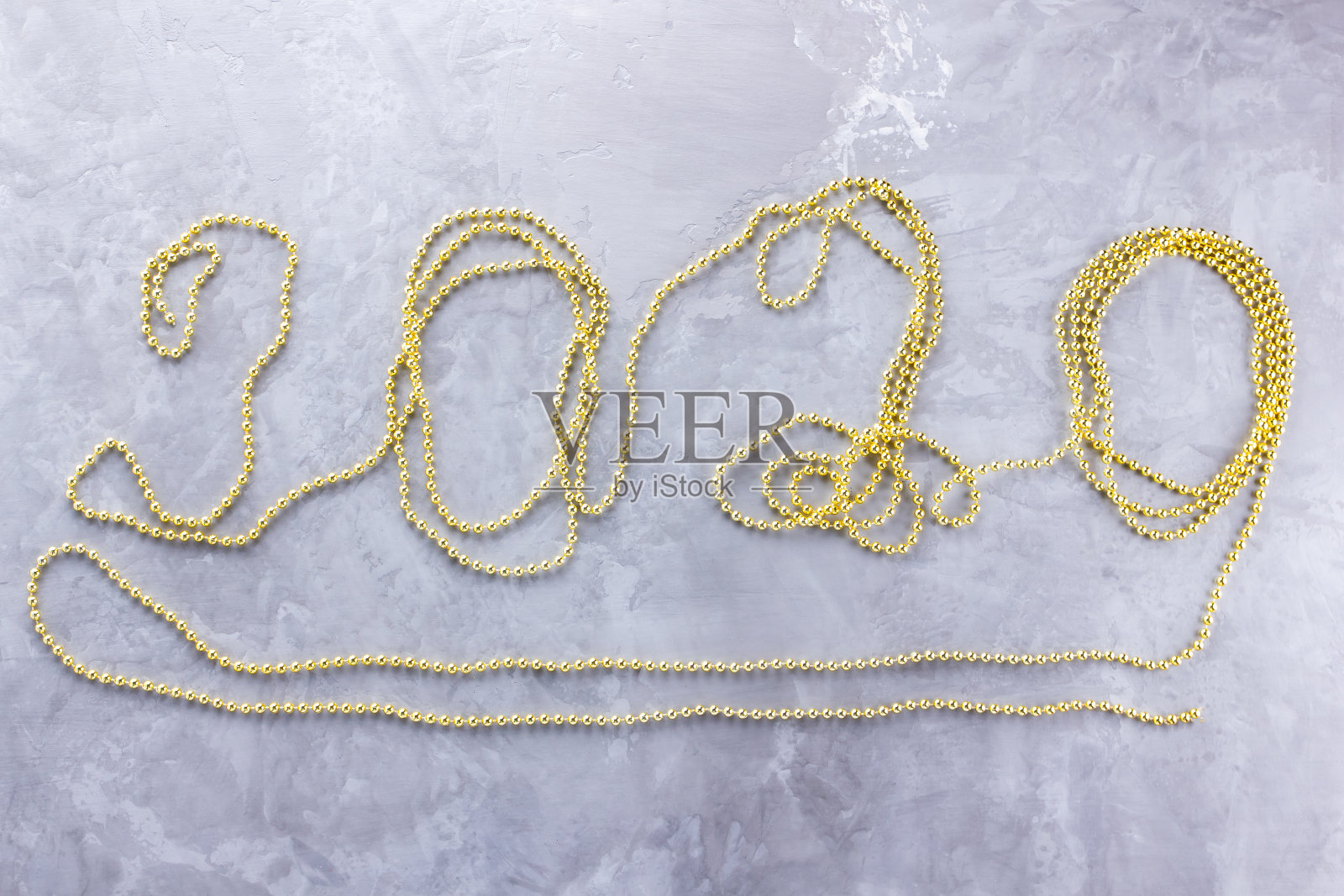 圣诞装饰。2020年新年人物，水泥背景金珠。圣诞概念与珠子。装饰设计圣诞与新年2020。前视图。平躺照片摄影图片