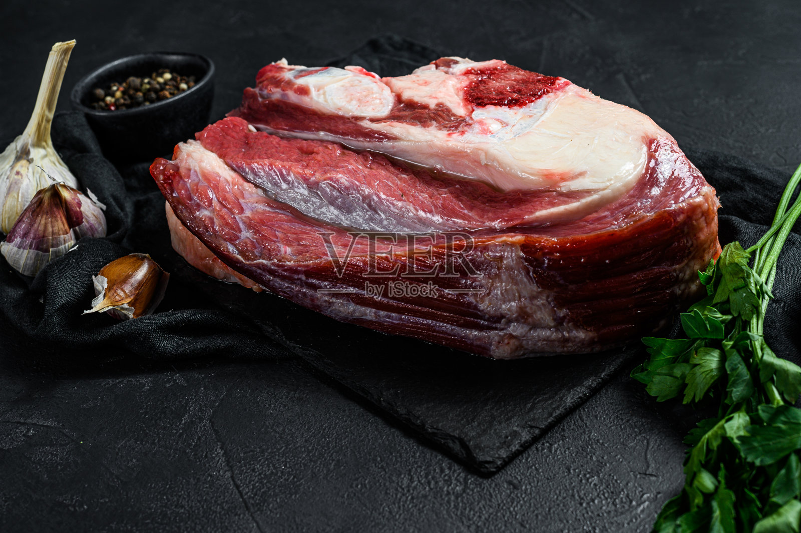 黑色背景上带骨的生牛肉。俯视图照片摄影图片