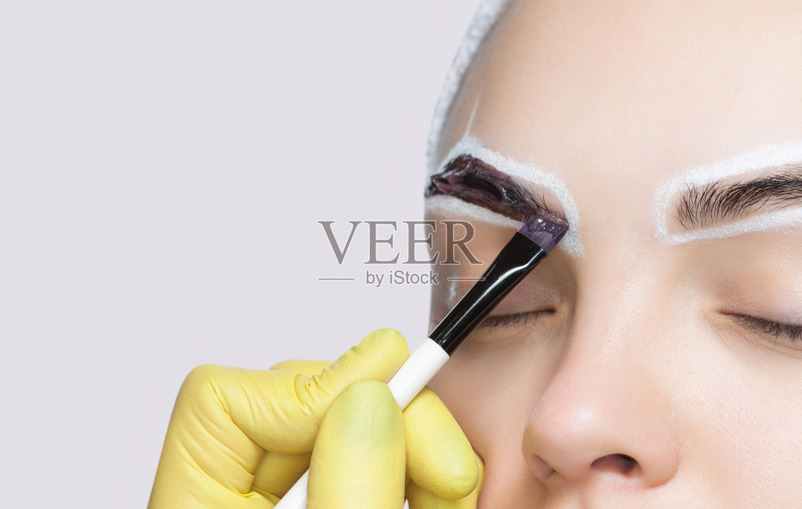 化妆师在一个小女孩的眉毛上涂了一种眉毛颜料。专业面临护理。照片摄影图片