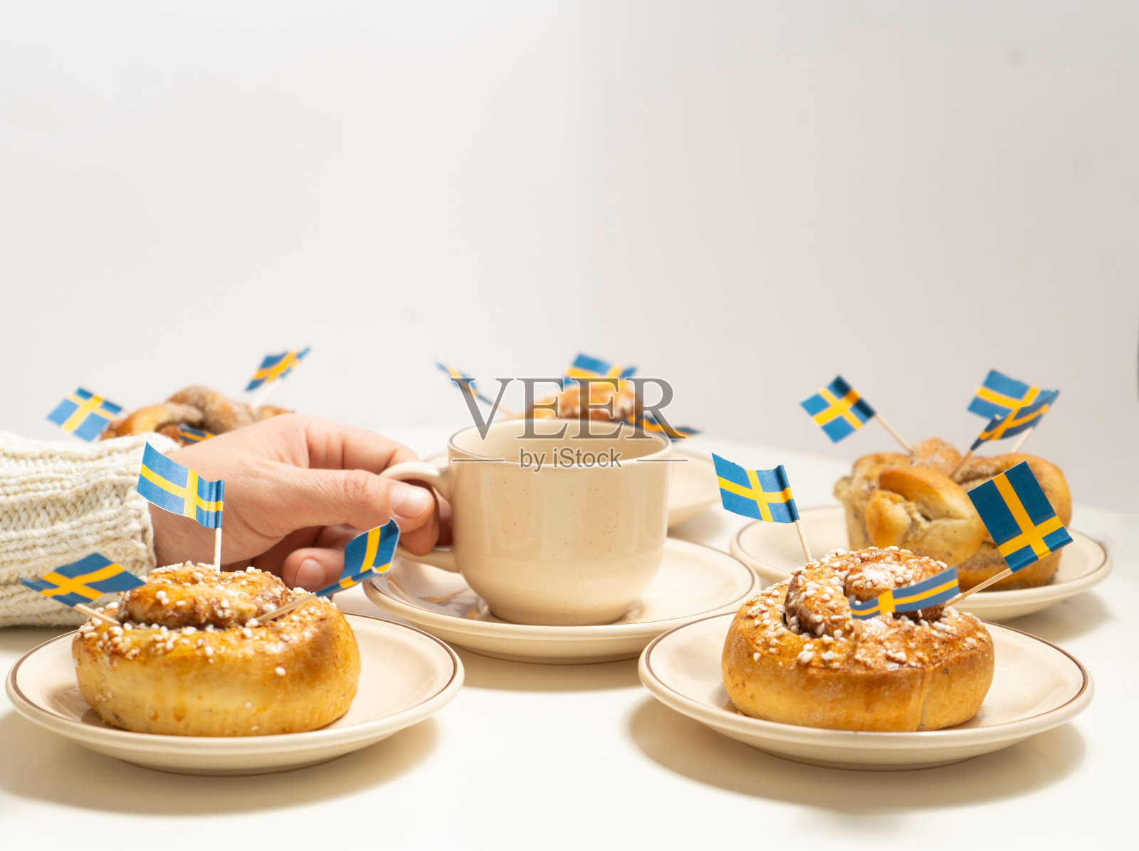 白色木桌上放着瑞典肉桂面包和咖啡杯。瑞典的国旗。照片摄影图片