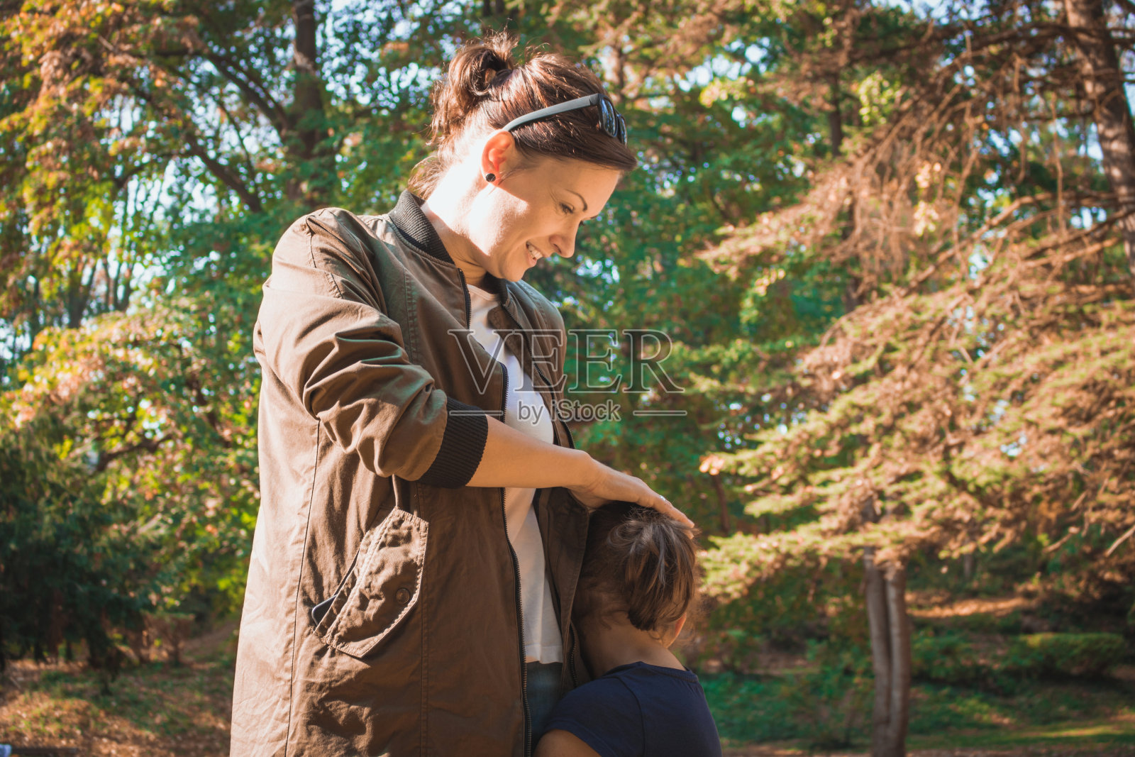 快乐的妈妈和她害羞的女儿在公园里。照片摄影图片