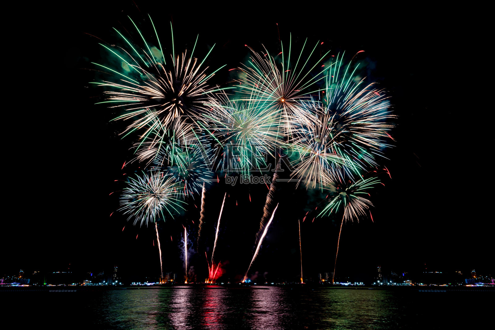 在庆祝之夜，令人惊叹的美丽多彩的烟花表演，展现在海滩上的多色倒影的水照片摄影图片