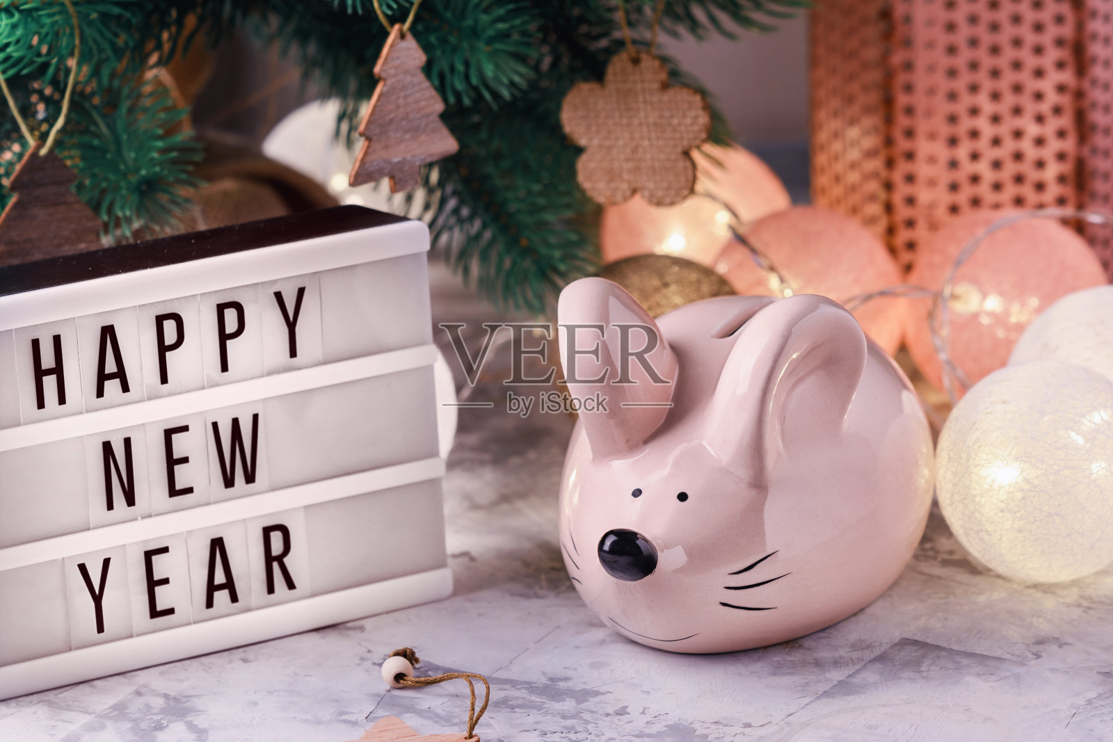 圣诞装饰品中的小装饰老鼠。上面写着新年快乐的灯箱。储蓄罐里的老鼠是一年的象征。照片摄影图片