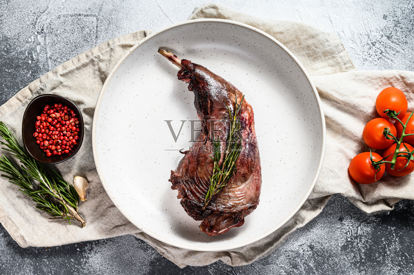农场兔子腿炖菜，配上新鲜的西红柿和迷迭香。灰色的背景。俯视图照片摄影图片