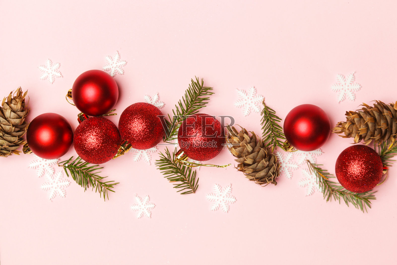 金色和红色的圣诞球和冷杉树枝在淡粉色的背景。圣诞装饰安排。照片摄影图片