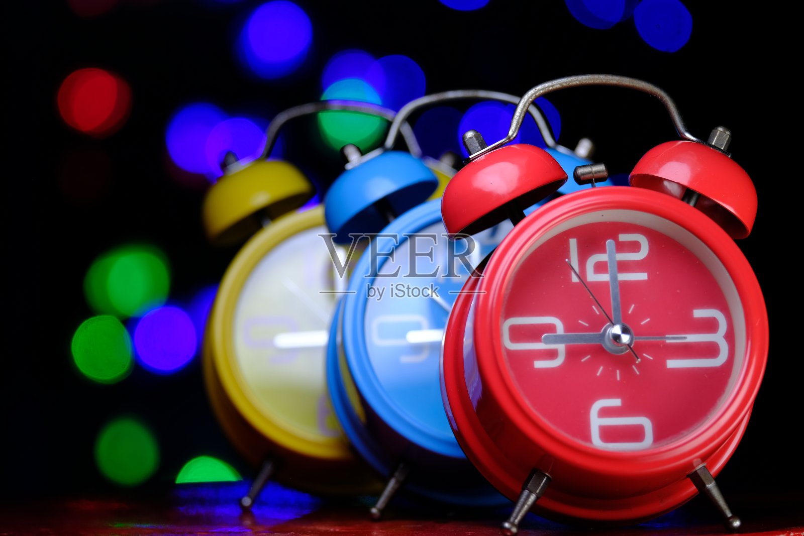 红色复古闹钟和蓝黄色模糊时钟照片摄影图片