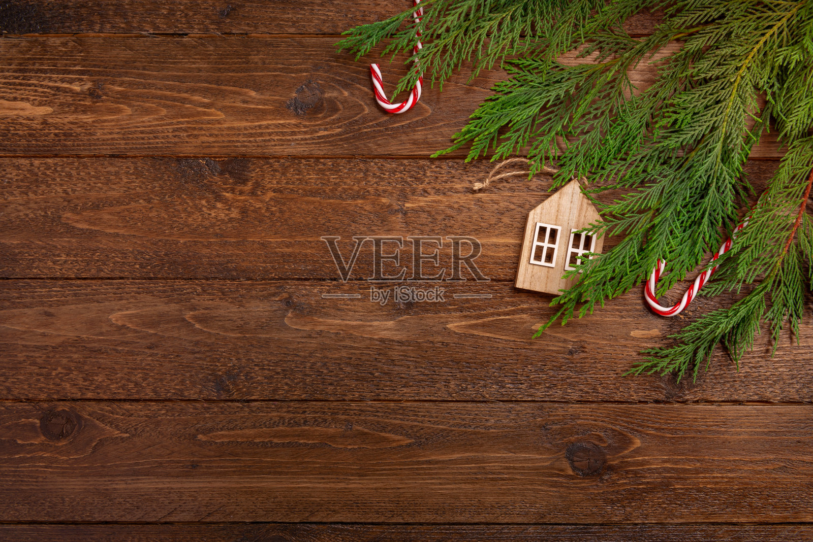 圣诞或新年平铺装饰背景:柏枝，木房子，糖果手杖，在黑暗的木制背景。顶视图框架模型与复制空间。照片摄影图片