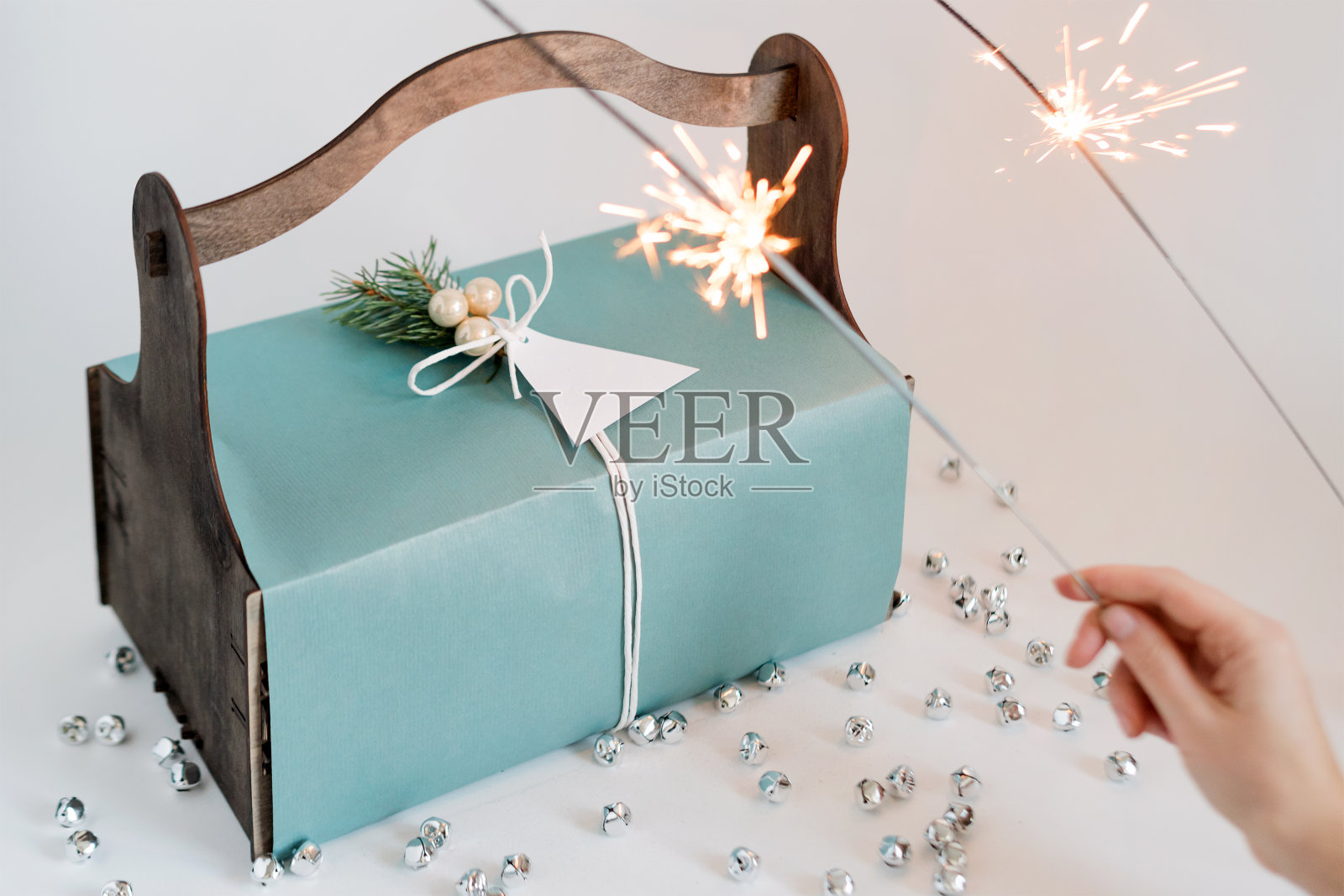 不认识的女人拿着装在木篮子里的圣诞礼物和烟花。快乐的寒假。圣诞庆祝的礼物。照片摄影图片